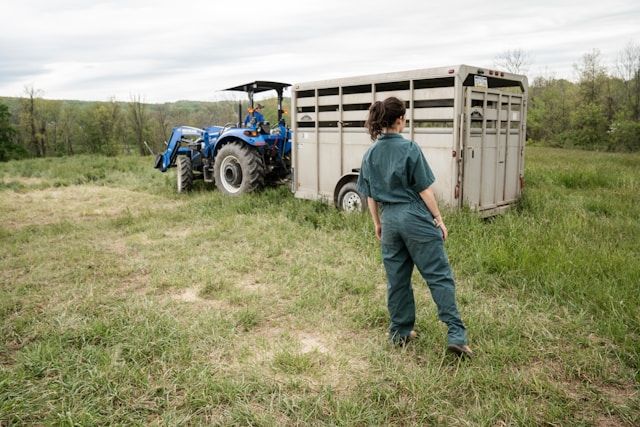 a farmer stands next to a tractor and trailer